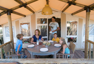 Gezin eet samen buiten aan hun tent bij SunLodge Safari, Camping Pra'delle Torri, Italië.