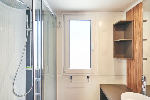 Salle de bain moderne au SunLodge Sabai avec cabine de douche, fenêtre, lavabo et étagères ouvertes.