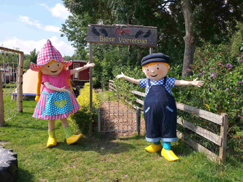 Dos coloridas mascotas dan la bienvenida a los visitantes en la entrada de Blote Voetenpad en Camping De Gouwe Stek.