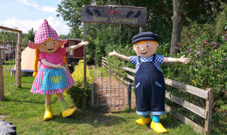 Dos coloridas mascotas dan la bienvenida a los visitantes en la entrada de Blote Voetenpad en Camping De Gouwe Stek.