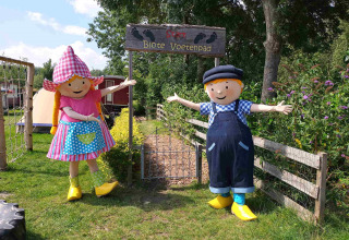 Two colorful mascots welcome visitors at the entrance of Blote Voetenpad in Camping De Gouwe Stek.