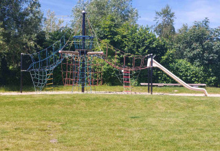 Speelterrein met klimrek en glijbaan bij Camping De Gouwe Stek, omgeven door natuur en groen.