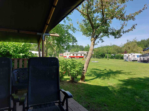 Vista de Camping De Gouwe Stek en Holanda del Norte con césped verde, caravanas y terraza sombreada.