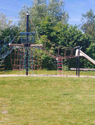 Parque infantil con redes para escalar y un tobogán al sol en Camping De Gouwe Stek, norte de Holanda.