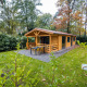Træhytte Wellness Lodge i Buitencentrum Hessenheem, Holland, omgivet af grønt og skov, med terrasse.