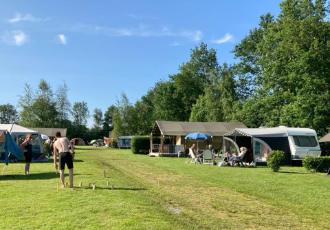 Vakantiepark Camping de Berghoeve in Drenthe, Nederland, waar mensen samen kamperen en buiten ontspannen.