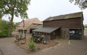 Billede af Camping de Berghoeve feriepark i Drenthe, Holland, med traditionelle bygninger og grønt område.