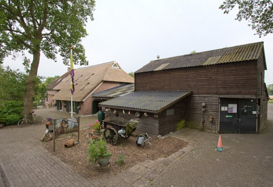 Billede af Camping de Berghoeve feriepark i Drenthe, Holland, med traditionelle bygninger og grønt område.