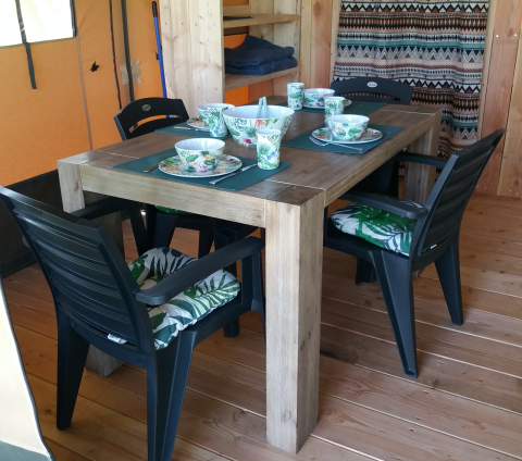 Mesa de comedor y sillas negras con vajilla en una tienda Stoere Safari en Camping de Berghoeve, Países Bajos.