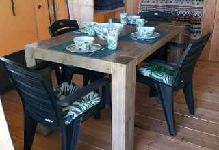 Mesa de comedor y sillas negras con vajilla en una tienda Stoere Safari en Camping de Berghoeve, Países Bajos.