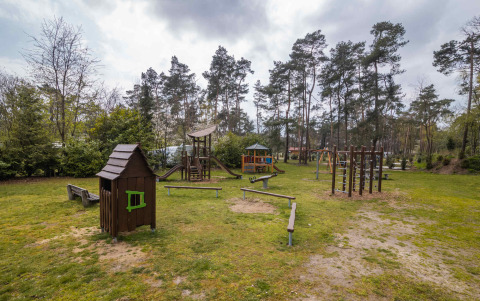 Spielplatz mit Holzhäuschen und Klettergeräten im Grünen im Ferienpark Buitencentrum Hessenheem, Overijssel.