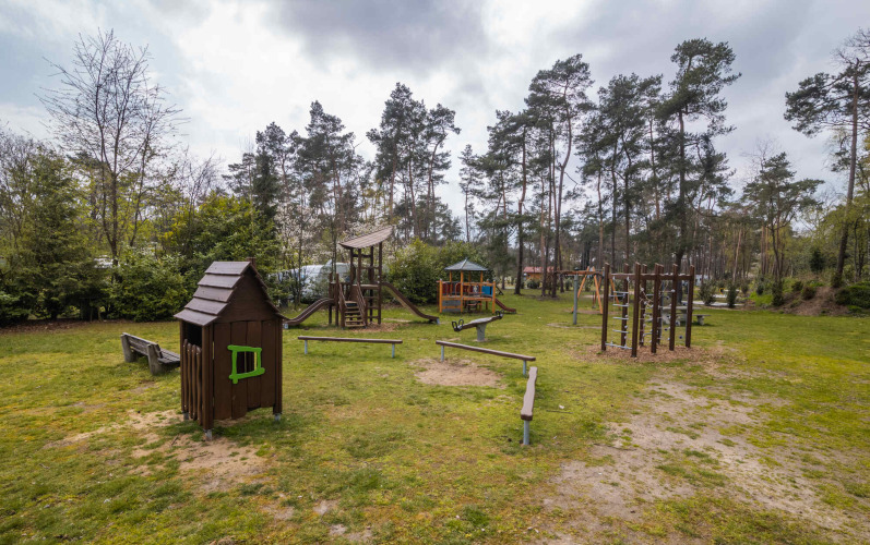 Outdoor playground with climbing structures, slides, and a playhouse at Buitencentrum Hessenheem, Overijssel.
