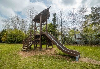Speelplein met glijbaan en trap bij Buitencentrum Hessenheem, omringd door bomen in Overijssel.