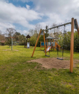 Parque infantil con columpios, tobogán y mesa de picnic en Buitencentrum Hessenheem, Overijssel.