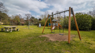 Spielplatz mit Schaukeln, Rutsche und Picknicktisch im Ferienpark Buitencentrum Hessenheem, Overijssel.