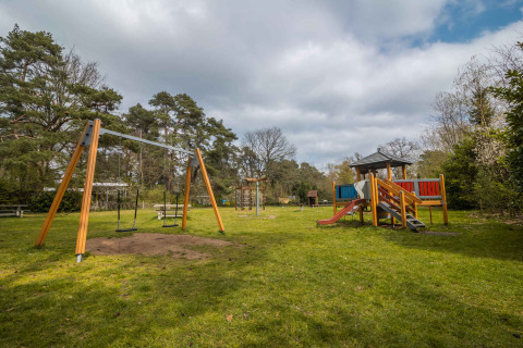 Aire de jeux au Buitencentrum Hessenheem, parc de vacances à Overijssel, Pays-Bas, avec balançoires et toboggan.