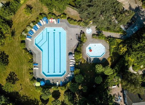 Vista aérea de piscinas y tumbonas en Buitencentrum Hessenheem, rodeadas de árboles en Overijssel, Países Bajos.