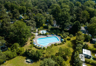 Vue aérienne de la piscine entourée d’arbres à Buitencentrum Hessenheem, parc de vacances à Overijssel, Pays-Bas.