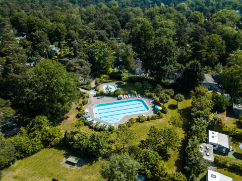 Vue aérienne de la piscine entourée d’arbres à Buitencentrum Hessenheem, parc de vacances à Overijssel, Pays-Bas.