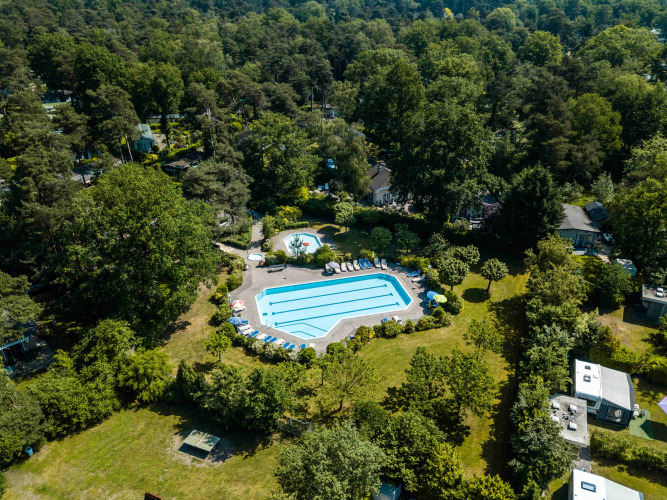 Aerial view of pool area surrounded by trees at Buitencentrum Hessenheem holiday park in Overijssel, Netherlands.