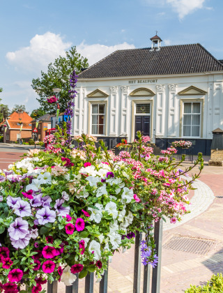 Blumenreicher Platz im Zentrum von Markelo, Overijssel, mit historischem weißen Gebäude im Sommer.