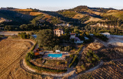 Vista aérea del parque vacacional Agricola La Casetta entre colinas y campos en la región de Las Marcas, Italia.