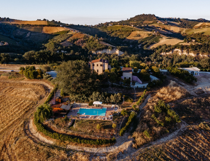 Luchtfoto van vakantiepark Agricola La Casetta, gelegen tussen heuvels en velden in Marche, Italië.