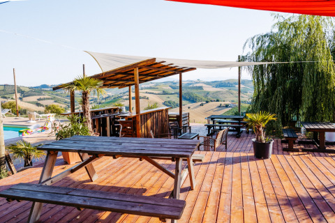 Houten terras met picknickbanken en uitzicht op de heuvels bij Agricola La Casetta, Marche, Italië.