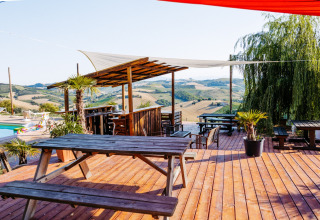 Træterrasse med bordbænkesæt og udsigt over bakkerne på Agricola La Casetta feriepark i Marche, Italien.