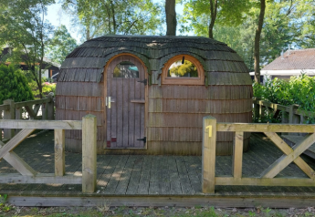 IGLO Log Cabin at Camping Emmen in the Netherlands, wooden structure on a deck surrounded by trees.
