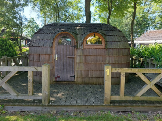 IGLO Log Cabin bij Camping Emmen in Nederland, houten hut op een vlonder, omringd door bomen.