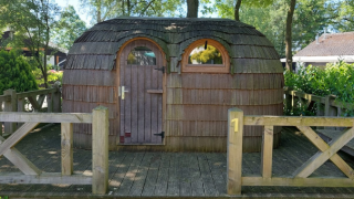 Eine IGLO Log Cabin auf dem Camping Emmen in den Niederlanden, gebaut aus Holz, mit Terrasse im Grünen.
