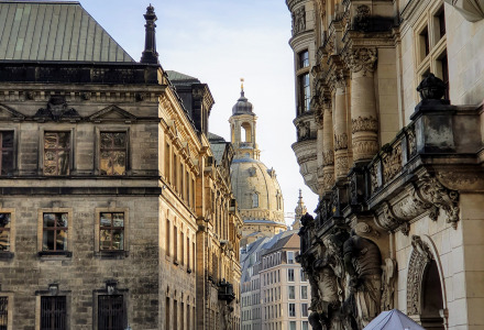 Gente paseando por una calle adoquinada rodeada de edificios históricos y un mercado local.