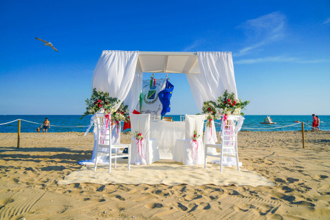Boda romántica en la playa en Union Lido Mare, Veneto, Italia, con decoración floral y vistas al mar.