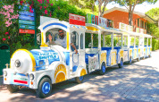 Un colorato trenino Union Lido Shuttle attraversa il villaggio turistico Camping Union Lido Mare in Veneto, Italia.