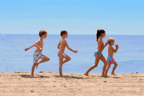 Niños jugando juntos en la playa de arena de Camping Union Lido Mare en Véneto, Italia, en un día soleado.