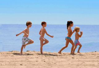 Kinderen spelen samen op het zandstrand bij Camping Union Lido Mare in Veneto, Italië, op een zonnige dag.