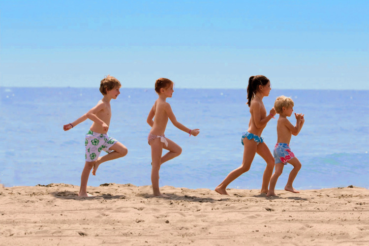 Des enfants jouent ensemble sur la plage de sable au Camping Union Lido Mare, en Vénétie, Italie, par beau temps.