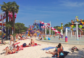 People sunbathing and playing near the water slides at Camping Union Lido Mare holiday park in Veneto, Italy.