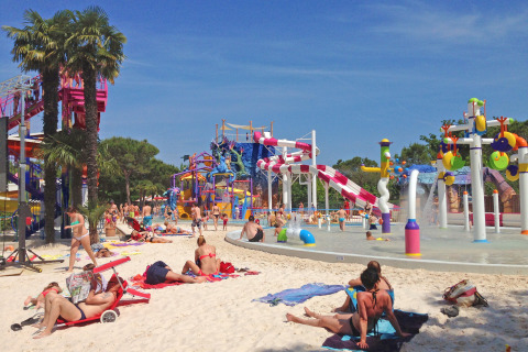 People sunbathing and playing near the water slides at Camping Union Lido Mare holiday park in Veneto, Italy.