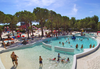 Folk nyder poolen og vandrutsjebanerne i Union Lido Mare feriepark omgivet af træer i Veneto, Italien.