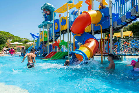 Children playing in a water park with colorful slides at Camping Union Lido Mare holiday park in Veneto, Italy.