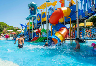 Children playing in a water park with colorful slides at Camping Union Lido Mare holiday park in Veneto, Italy.