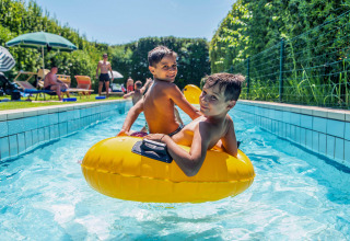 Due bambini si divertono su un gonfiabile giallo nella piscina del Camping Union Lido Mare in Veneto, Italia.