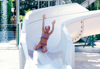 Bambina in costume scivola su uno scivolo d'acqua a Camping Union Lido Mare, parco vacanze in Veneto.