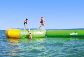 Children playing on a Wibit inflatable water park at Camping Union Lido Mare, Veneto, Italy, on a sunny day.