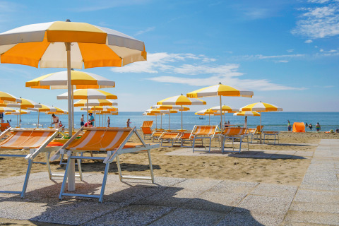 Zonnige ligstoelen en parasols op het strand bij Camping Union Lido Mare in Veneto, Italië.