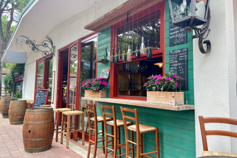 Outdoor bar area at Camping Union Lido Mare, Veneto, Italy with high stools, wine barrels, and flowers.
