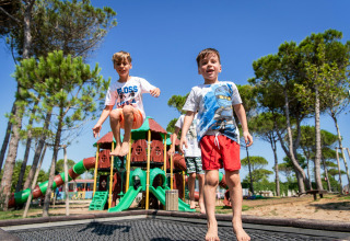 Bambini che giocano e saltano sul trampolino nel parco giochi di Camping Union Lido Mare, Veneto, Italia.
