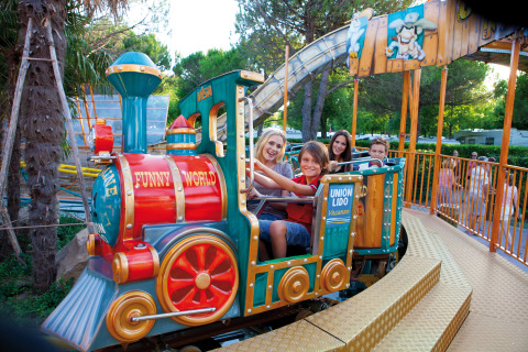 Famiglia si diverte su un trenino colorato al Camping Union Lido Mare, villaggio turistico in Veneto, Italia.